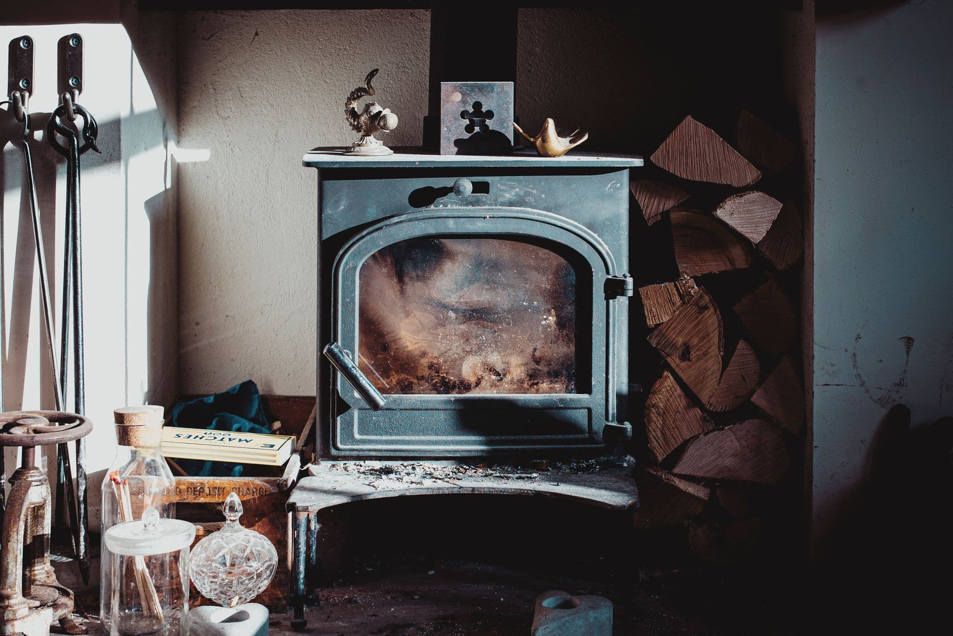 Aged vintage fireplace placed on table in rustic house near pile of firewood on sunny day